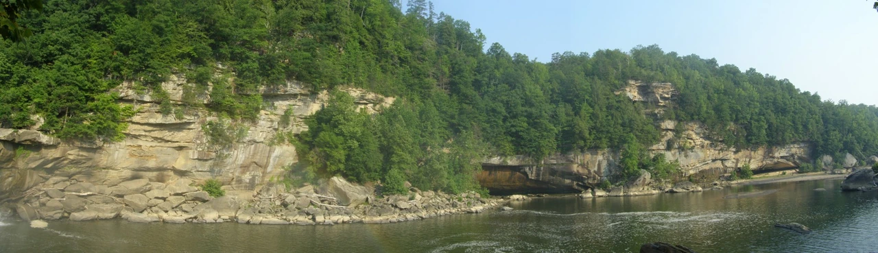 A broad Cumberland River panorama with layered rock cliffs and green forest.